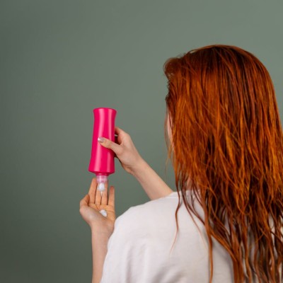 Woman Applying Hair Conditioner from Red Bottle