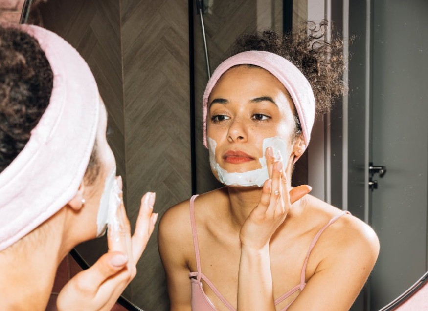 girl washing face in front of mirror