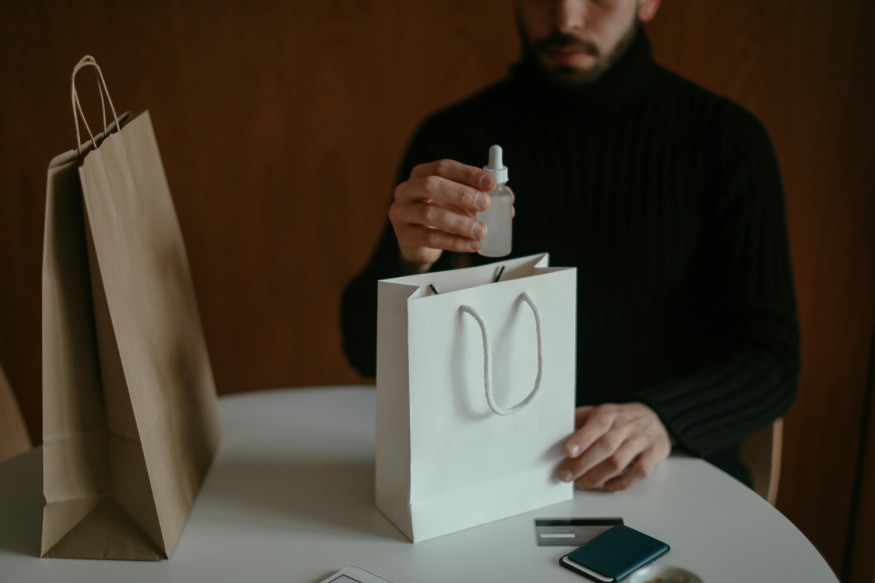 Man with beard oil in hand removing from bag