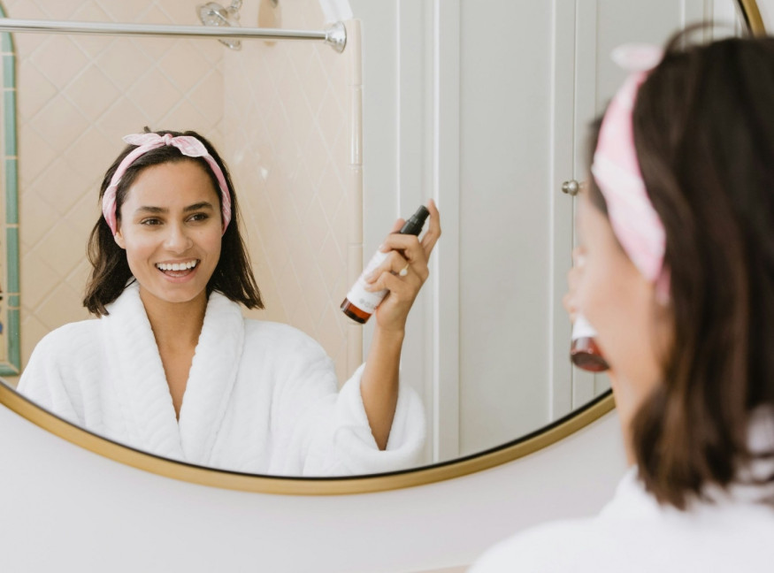 girl with pink headband applying facial spray