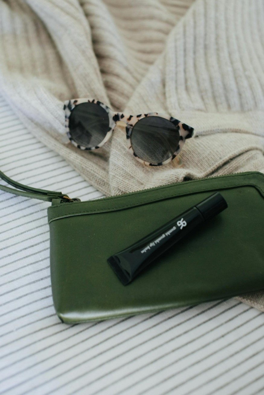 lip balm in a tube with green wrislet and sunglasses